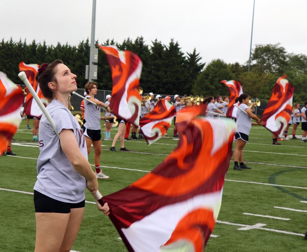 ms. hepner waving a virginia tech flag as a member of the color guard. she wears a grey tee shirt and black shorts