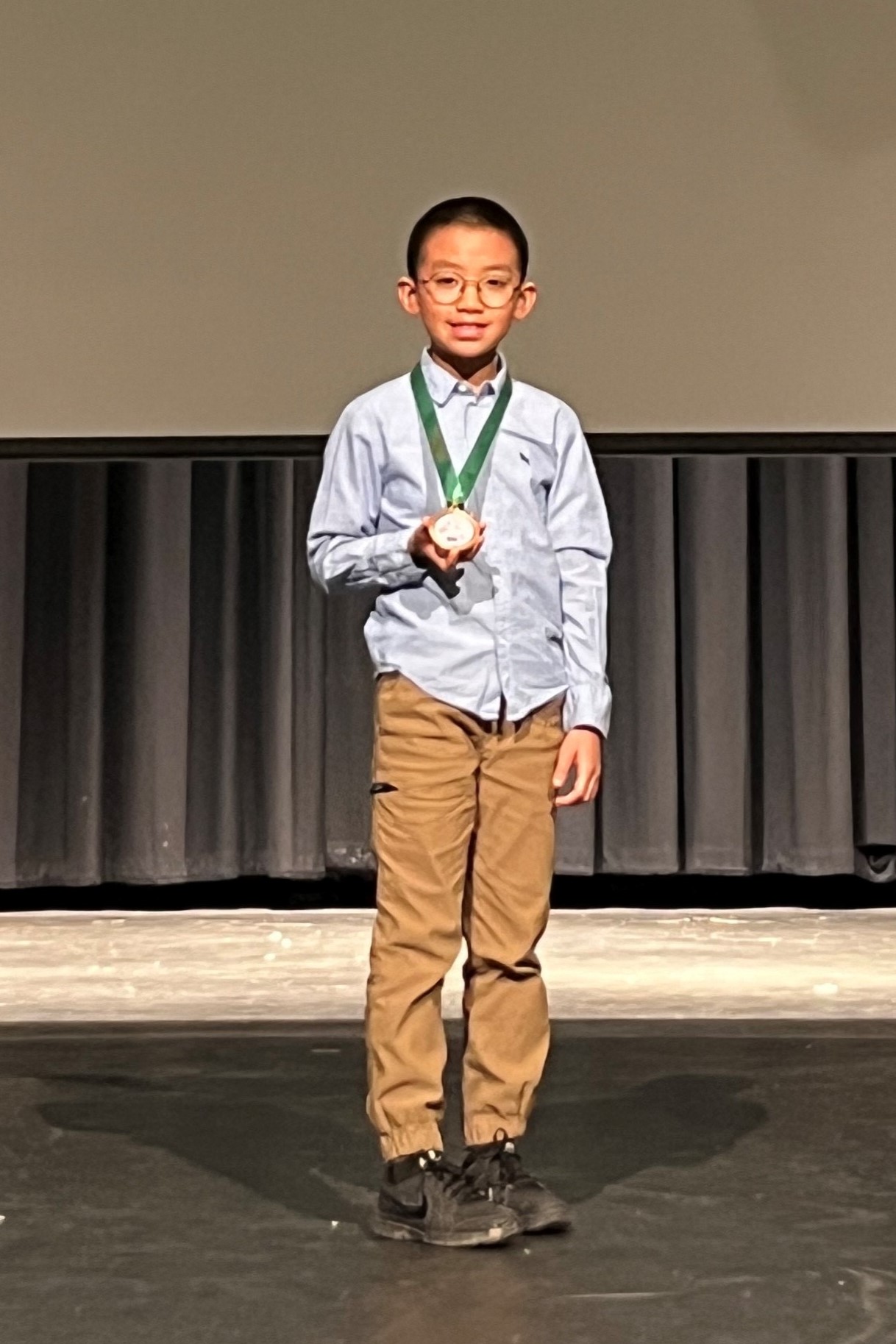 a student honoree poses on stage with his award